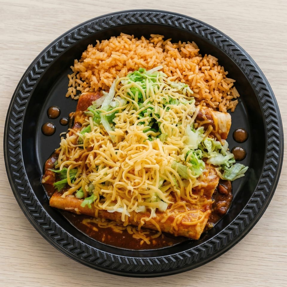 Two enchiladas covered in sauce, cheese, and lettuce, with a side of rice on a black plate.