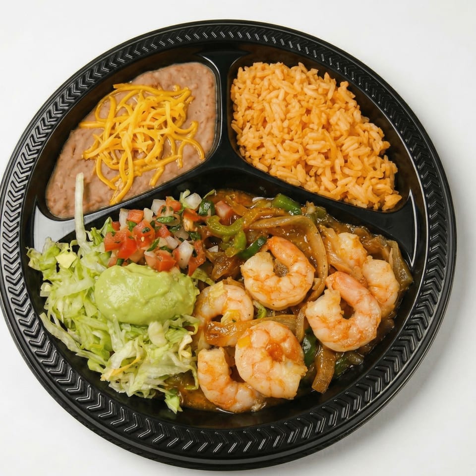 Shrimp fajita platter with rice, refried beans, guacamole, pico de gallo, and shredded lettuce.